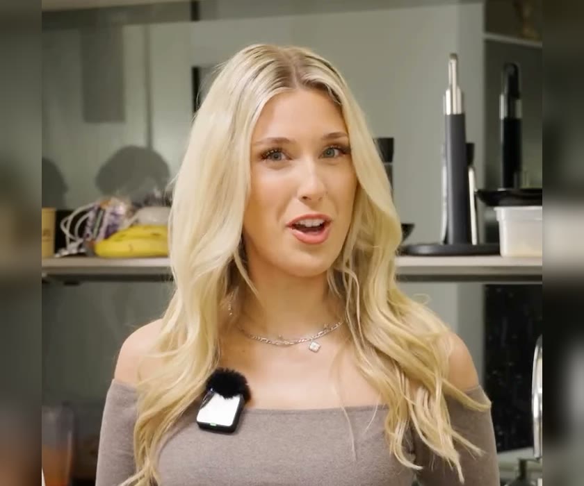 A presenter with a clip-on microphone, filmed upright in a kitchen